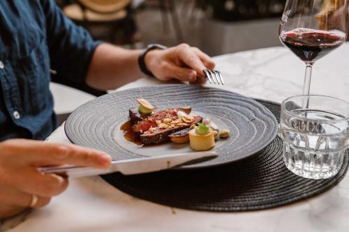 a person holding a knife and a plate of food at Grand Boutique Hotel-Restaurant Huis Vermeer in Deventer