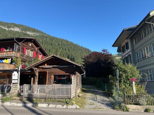 a building with a fence in front of a mountain at Region de Gstaad - Ultra Modern Apartment- Huge Roof Terrace - Great Views in Zweisimmen