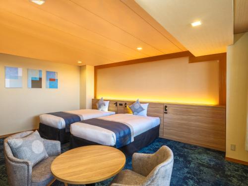 a hotel room with two beds and a table and chairs at KAMENOI HOTEL Oarai in Oarai