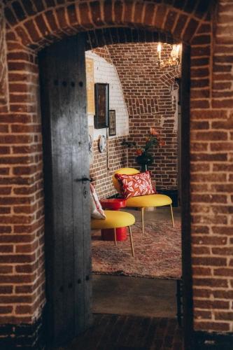 a brick room with two chairs and a couch at Fort Vuren in Vuren