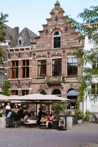 a building with people sitting in front of it at Grand Boutique Hotel-Restaurant Huis Vermeer in Deventer