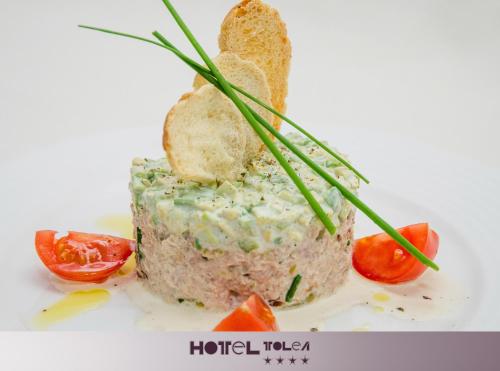 a piece of food on a plate with tomatoes at Hotel Tolea in Târgovişte