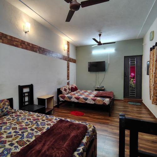 a hotel room with two beds and a flat screen tv at 4M FarmStay in Bodināyakkanūr