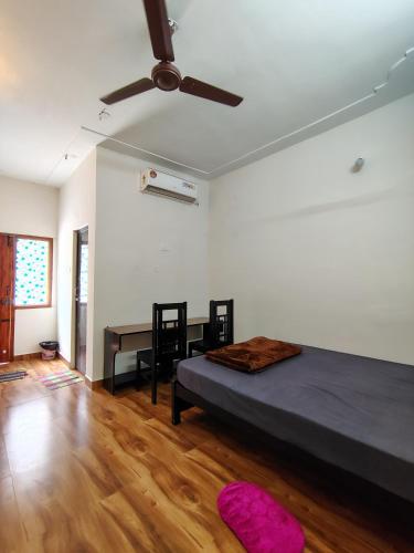 a bedroom with a bed and a desk and a ceiling fan at 4M FarmStay in Bodināyakkanūr