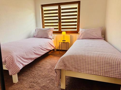 two beds in a room with a window at Apartman Zlata - free parking in Sarajevo