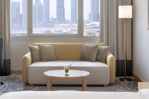 a living room with a couch and a table at Swissôtel Al Murooj Dubai in Dubai