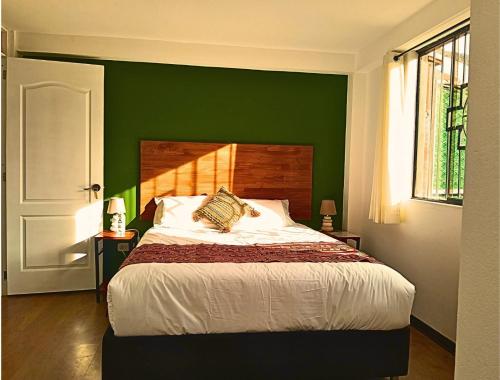 a bedroom with a green wall and a bed at Hotel and Country House Valle Sagrado de los Incas in Huaran