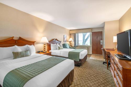 a hotel room with two beds and a flat screen tv at The Inn at Gran View Ogdensburg, an Ascend Collection Hotel in Ogdensburg