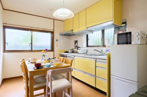 a kitchen with yellow cabinets and a white refrigerator at Family Garden House Tokyo Machida in Machida