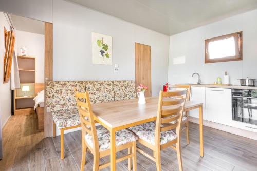 a kitchen and dining room with a wooden table and chairs at Terme Banovci - Mobilne hiške Med Brajdami in Banovci