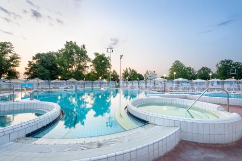 a large swimming pool with chairs around it at Terme Banovci - Mobilne hiške Med Brajdami in Banovci