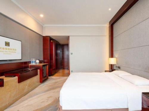 a bedroom with a large white bed and a tv at Grand Metropark Hotel Chongqing in Chongqing