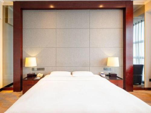 a bedroom with a large white bed and two lamps at Grand Metropark Hotel Chongqing in Chongqing