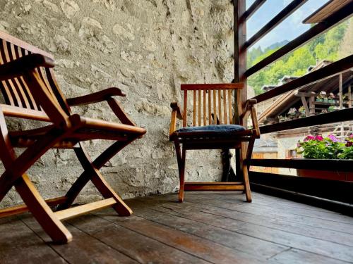 two rocking chairs sitting on a porch with a window at La Tana dell'Orso in Forni di Sopra