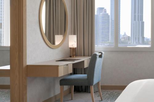 a desk in a hotel room with a mirror at Swissôtel Al Murooj Dubai in Dubai