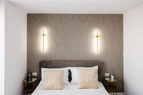 a bedroom with a bed with two lamps on the wall at Premium Tulip Aparthotel close to Airport & Therme in Tunari