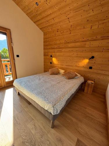 a bedroom with a bed in a wooden wall at Chalet PIERRA MENTA ski & commodités in Taninges