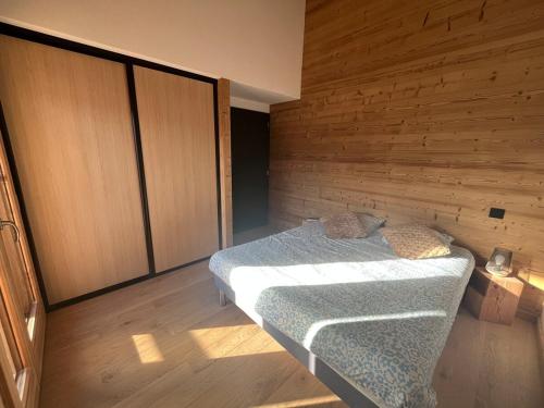 a bedroom with a bed and a wooden wall at Chalet PIERRA MENTA ski & commodités in Taninges