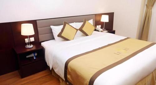 a large bed in a hotel room with two lamps at Lenid Hotel Tho Nhuom in Hanoi