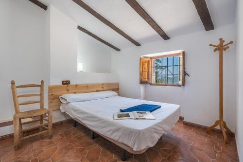 1 dormitorio con 1 cama, 1 silla y 1 cruz en El Ventorro, en Granada