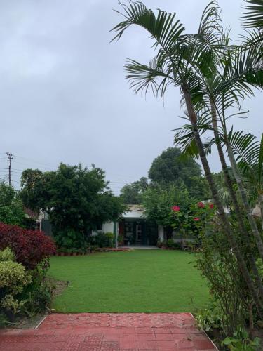a palm tree in front of a house with a lawn at Green Serene Abode in Meerut