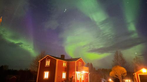 an orange house with the aurora in the sky at Cozy Family Villa for aurora lovers in Byske