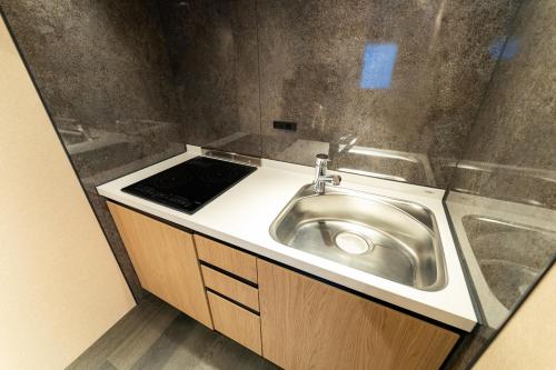 a stainless steel sink in a small bathroom at Koala Inn Ueno in Tokyo