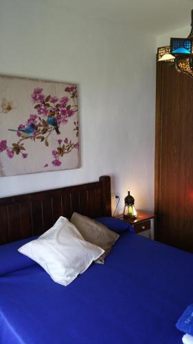 a bedroom with a blue bed with a painting on the wall at Barlovento Tres, Los Caños in Los Caños de Meca