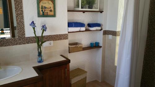 uma casa de banho com um lavatório e um vaso com flores roxas em Barlovento Tres, Los Caños em Los Caños de Meca