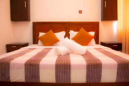 a bedroom with a large bed with orange and white pillows at Cieloblu In Hotel Matara in Palatuwa