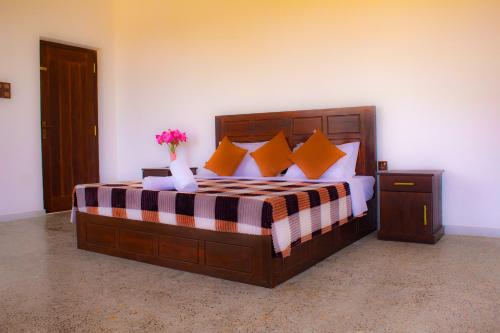 a bedroom with a large wooden bed with orange pillows at Cieloblu In Hotel Matara in Palatuwa