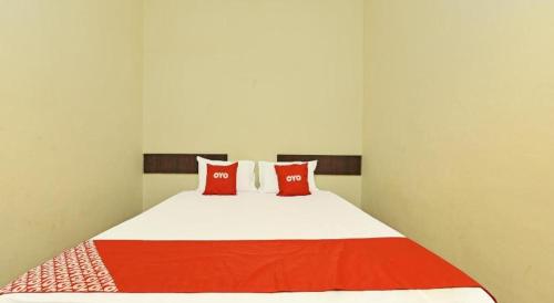 a bed with two red pillows on top of it at SPOT ON 91178 Motel Impian in Seri Manjung