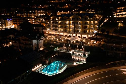 a building with a swimming pool at night at Alpenresort Belvedere in Molveno