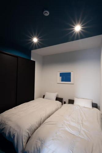 two beds in a room with lights on the ceiling at ほうしんノマ HOUSHIN noma in Osaka