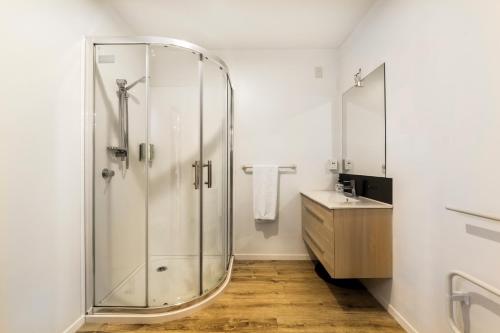 a bathroom with a glass shower and a sink at Harewood Lodge in Christchurch