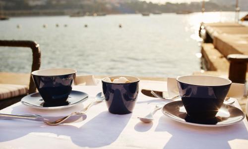 two coffee cups sitting on a table near the water at Welcome Hotel in Villefranche-sur-Mer