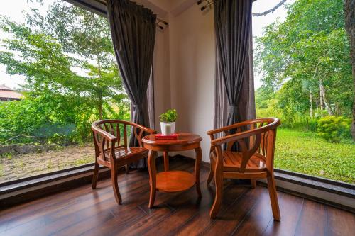 a room with a table and two chairs and a window at Open Hotel by Olive - Biranji Aqua Reatreat in Chikmagalūr
