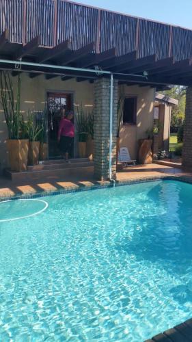 a large blue swimming pool in front of a house at Texas Guesthouse in Phalaborwa