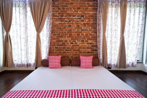 a bed with red and white pillows in front of a brick wall at Open Hotel by Olive - Biranji Aqua Reatreat in Chikmagalūr