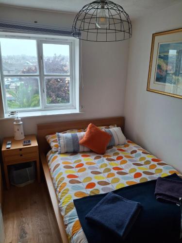 a bedroom with a bed and a desk and two windows at Marina View South Facing Balcony Sunny Apartment in East Cowes