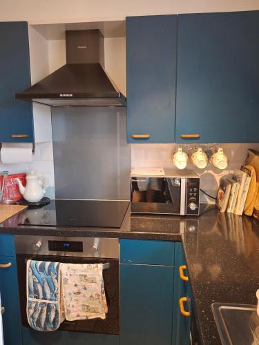 a kitchen with blue cabinets and a black counter top at Marina View South Facing Balcony Sunny Apartment in East Cowes