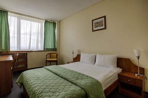 a hotel room with a bed and a desk and a window at Hemus Hotel Sofia in Sofia