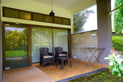 a patio with two chairs and a table on it at Open Hotel by Olive - Biranji Aqua Reatreat in Chikmagalūr