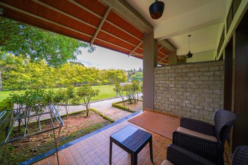 a patio with a table and chairs on a porch at Open Hotel by Olive - Biranji Aqua Reatreat in Chikmagalūr