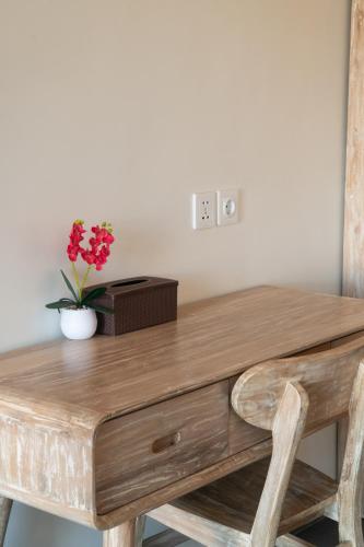 a wooden desk with a vase of flowers on it at Sundari Bali Guest House in Munggu