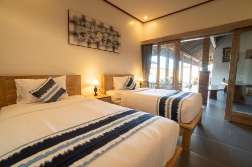 a bedroom with two beds and a window at Sundari Bali Guest House in Munggu