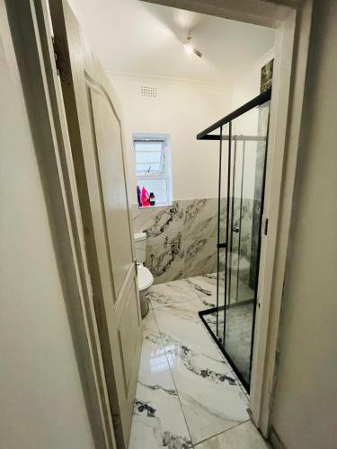 a bathroom with a toilet and a glass door at Lux Sleek City Haven in Cape Town