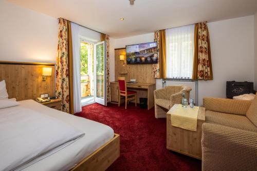 a hotel room with a bed and a desk at Alm- & Wellnesshotel Alpenhof in Schönau am Königssee