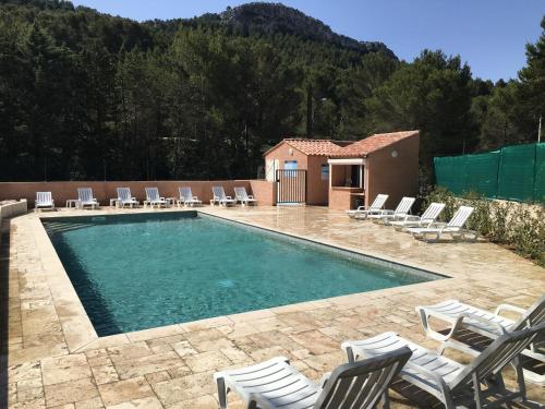 a swimming pool with chairs and a house at Camping Aux Portes De Cassis in La Bédoule