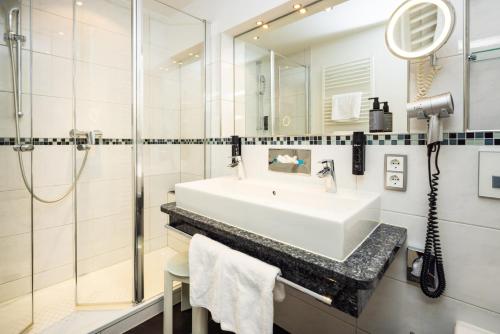 a white bathroom with a sink and a shower at Alm- & Wellnesshotel Alpenhof in Schönau am Königssee